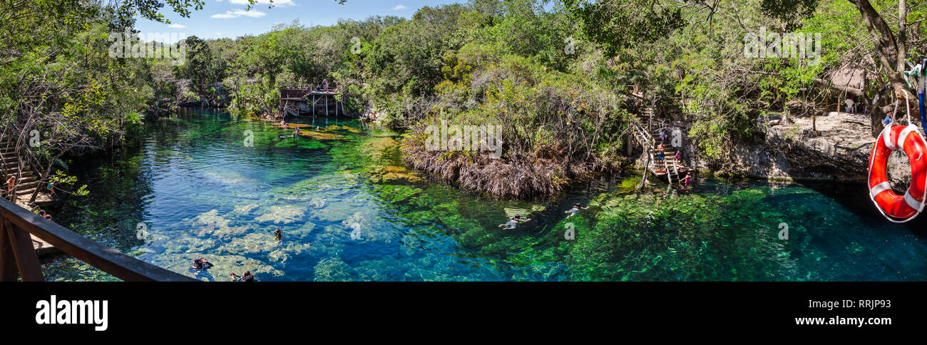 El Jardin del Eden cenote extérieure avec des nageurs (visages flous) et la jungle environnante. Banque D'Images