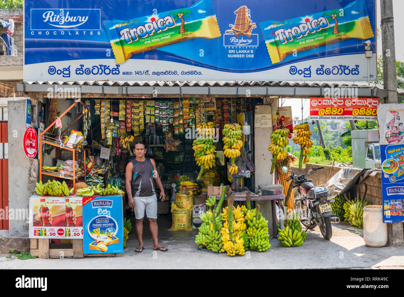 Sur Kalapaluwawa Road à Rajagiriya, un propriétaire de boutique attend pour passage à l'avant de son Kade à Colombo, Sri Lanka. Banque D'Images