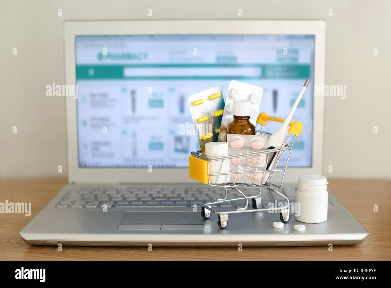 Panier jouet avec des médicaments devant un écran d'ordinateur portable avec pharmacie site web sur elle. Comprimés, blisters, flacons, thermomètre médical défini. Hea Banque D'Images
