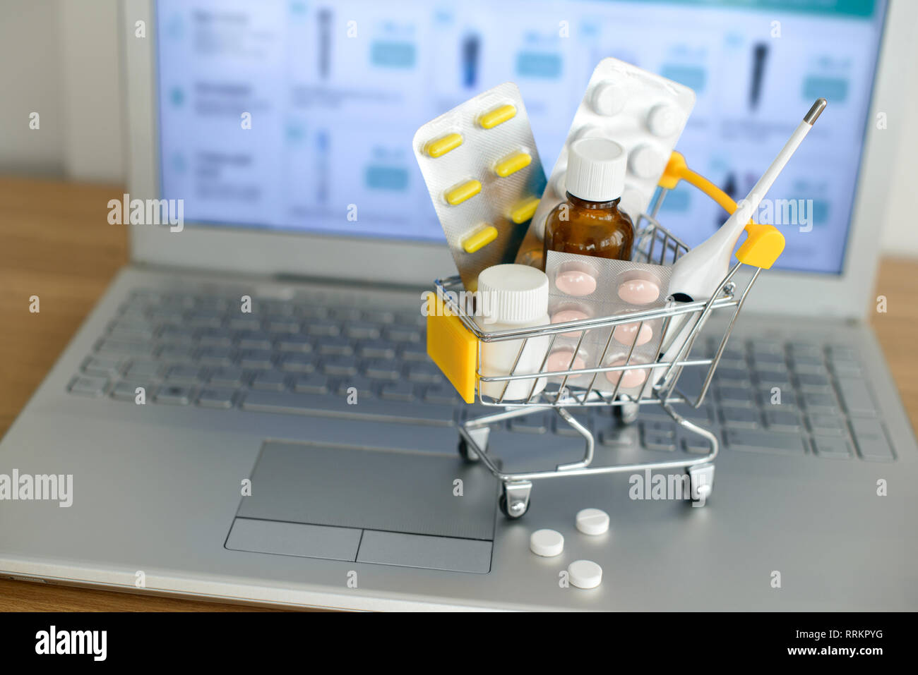 Panier jouet avec des médicaments devant un écran d'ordinateur portable avec pharmacie site web sur elle. Comprimés, blisters, flacons, thermomètre médical défini. Hea Banque D'Images