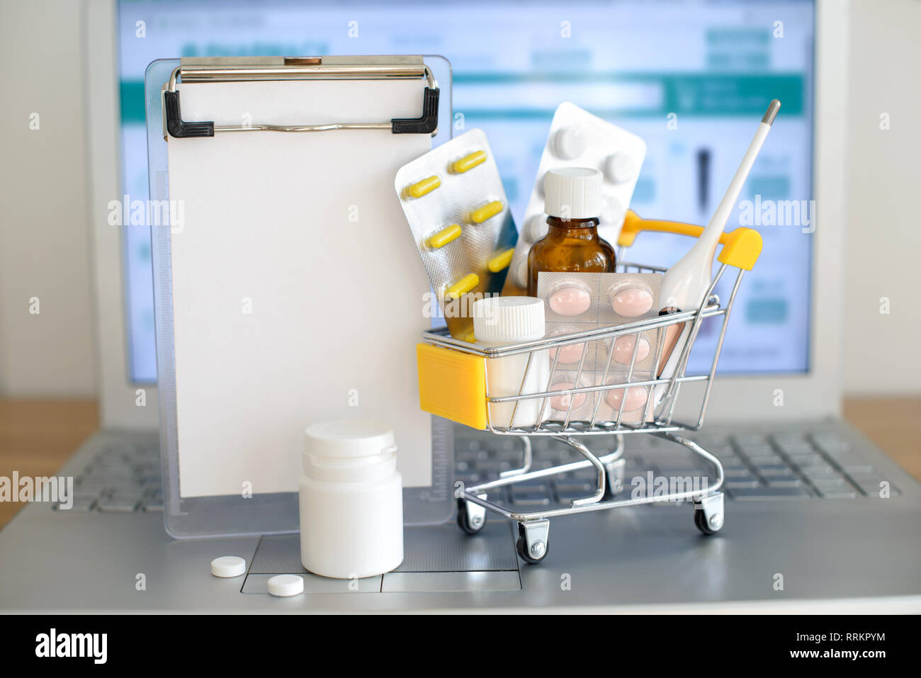 Panier jouet avec des médicaments et du papier remarque devant un écran d'ordinateur portable avec pharmacie site web sur elle. Comprimés, blisters, flacons médical, therm Banque D'Images