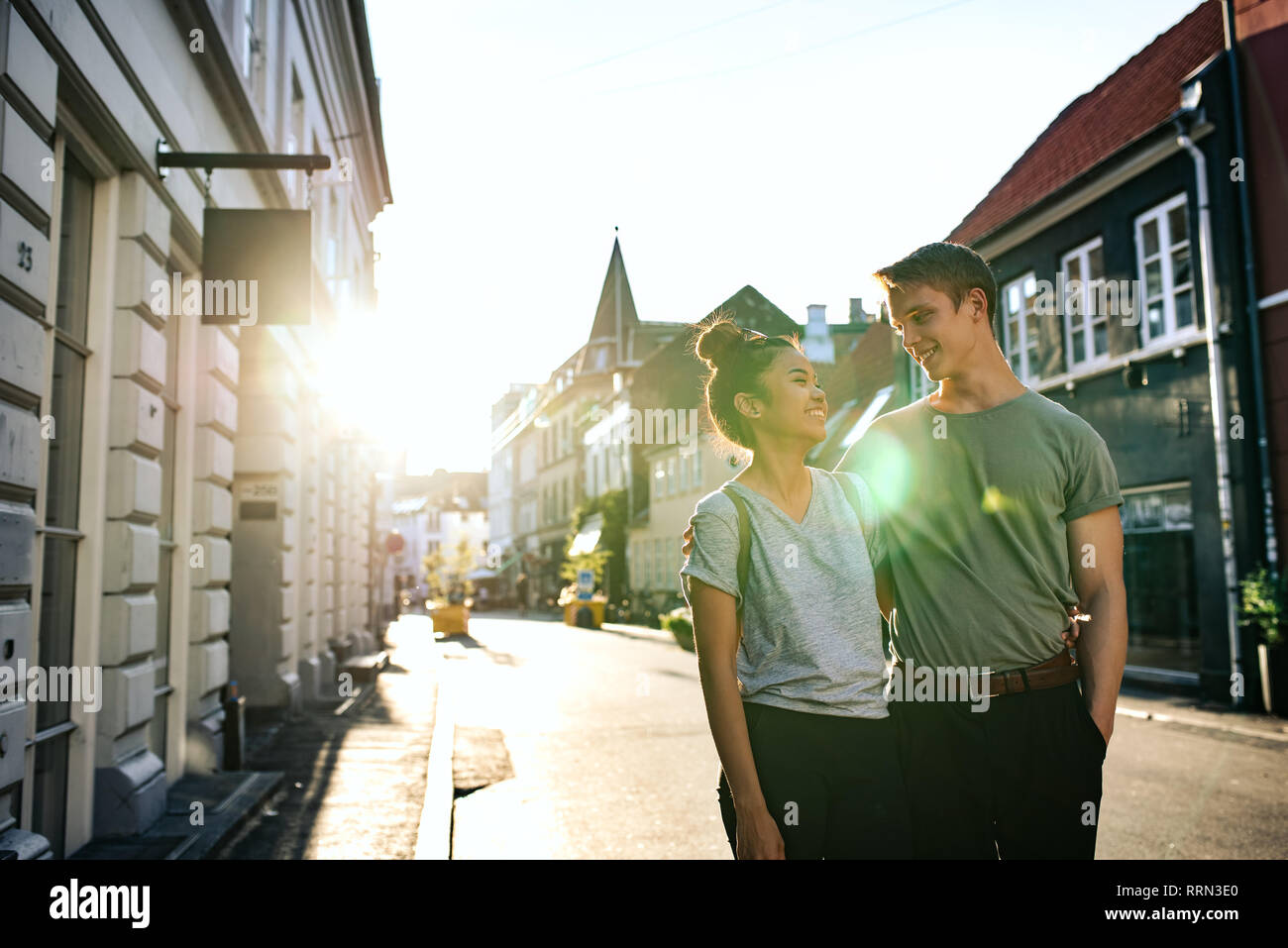 Laughing young couple marcher ensemble le long d'un trottoir de la ville Banque D'Images