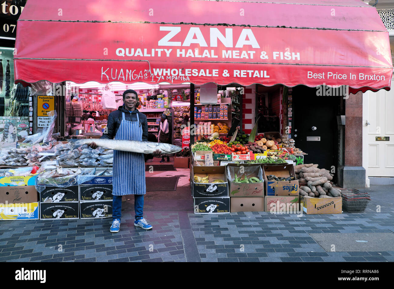 Electric Avenue Brixton street market un homme travailleur ayant barracuda poisson en dehors de la viande halal Zana & poisson dans le sud de Londres SW9 England UK KATHY DEWITT Banque D'Images