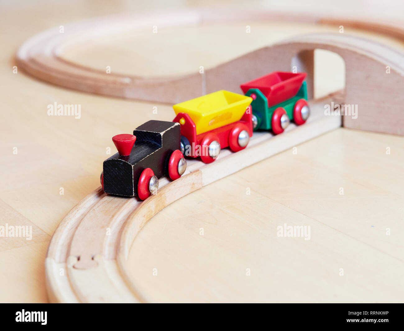 Circulation du train jouet en bois sur fer miniature. Le moteur noir tirant voitures colorées sur le sol. Jouets éducatifs pour les enfants en maternelle et de ki Banque D'Images