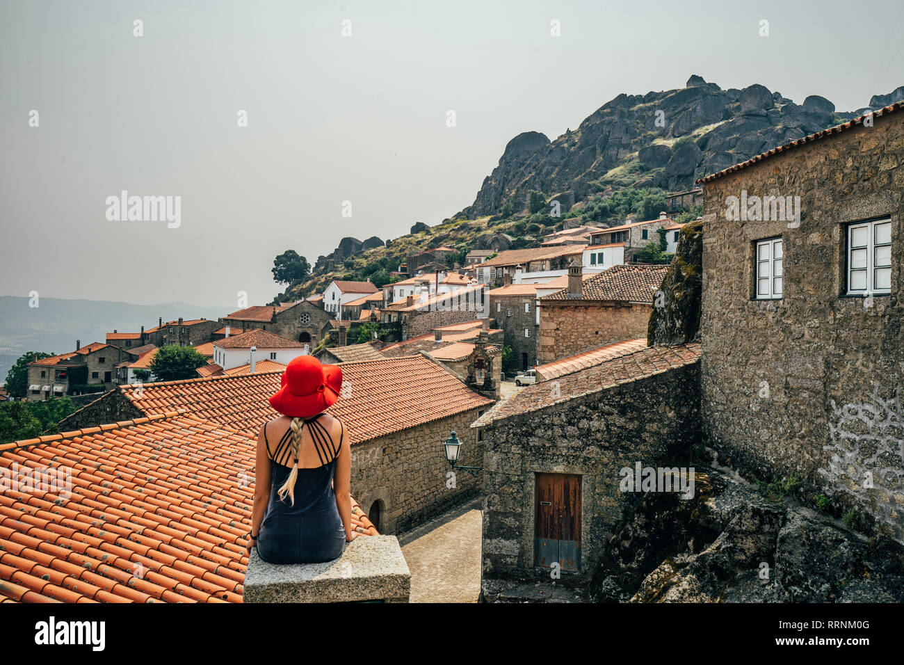 Woman in red hat looking at bâtiments sur colline, Monsanto, Portugal Banque D'Images