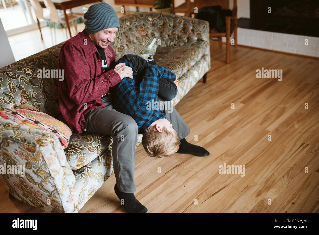 Père ludique holding fils envers sur salon canapé Banque D'Images