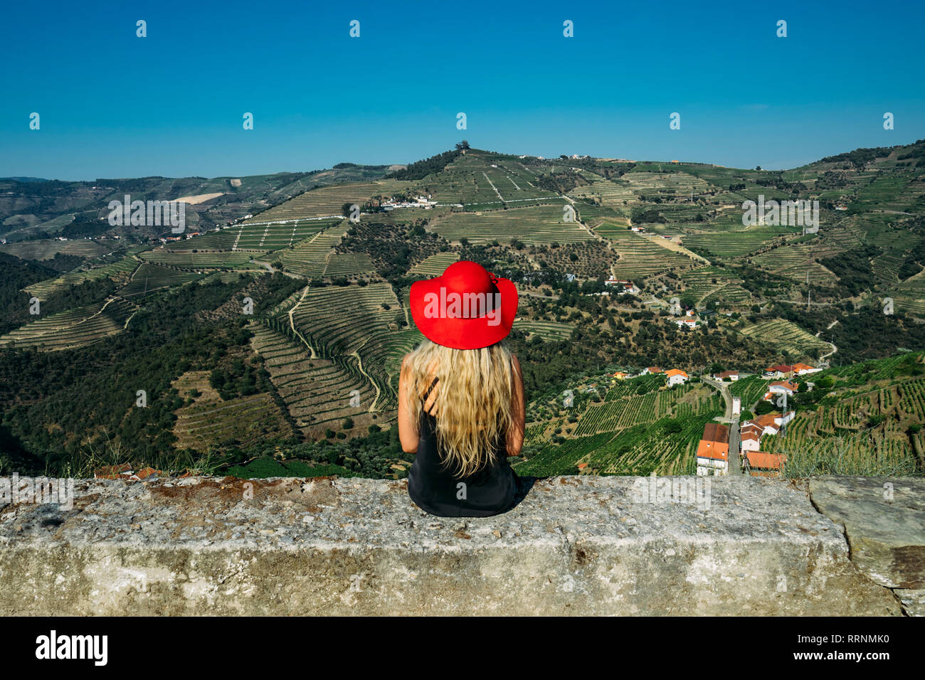 Woman in red hat appréciant ensoleillée, vaste paysage vallonné, vue sur le Portugal Banque D'Images