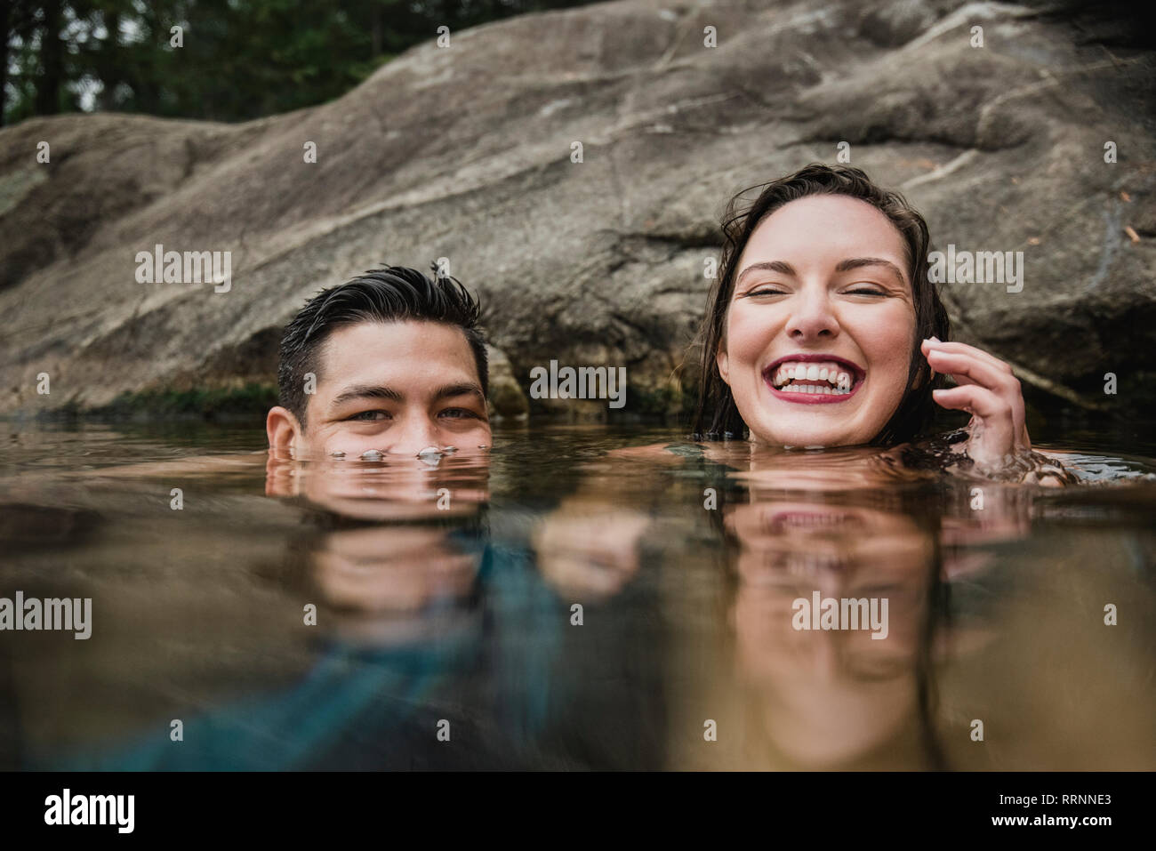 Portrait jeune couple ludique nager dans le lac Banque D'Images