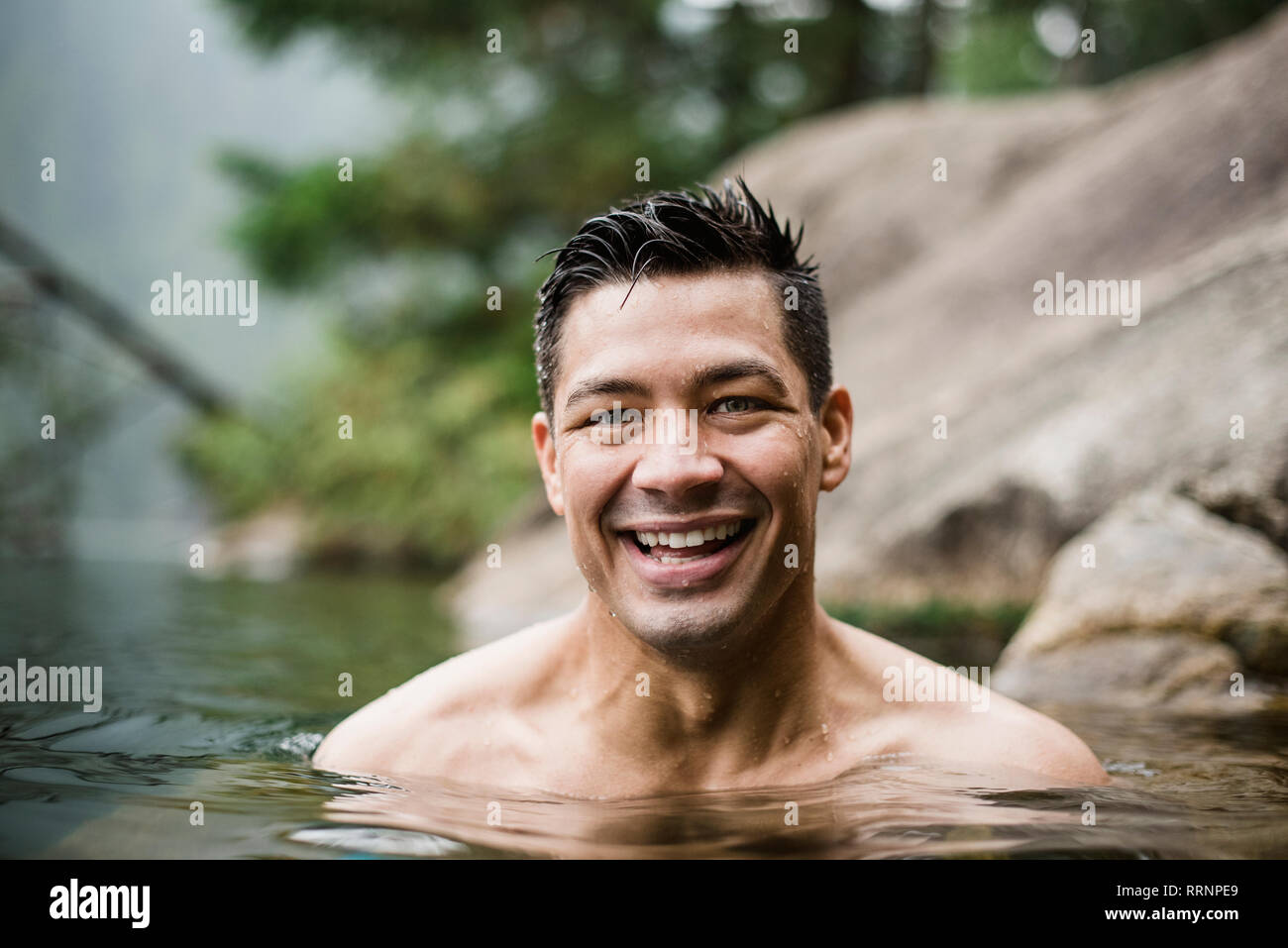 Portrait souriant, beau jeune homme nager dans le lac Banque D'Images