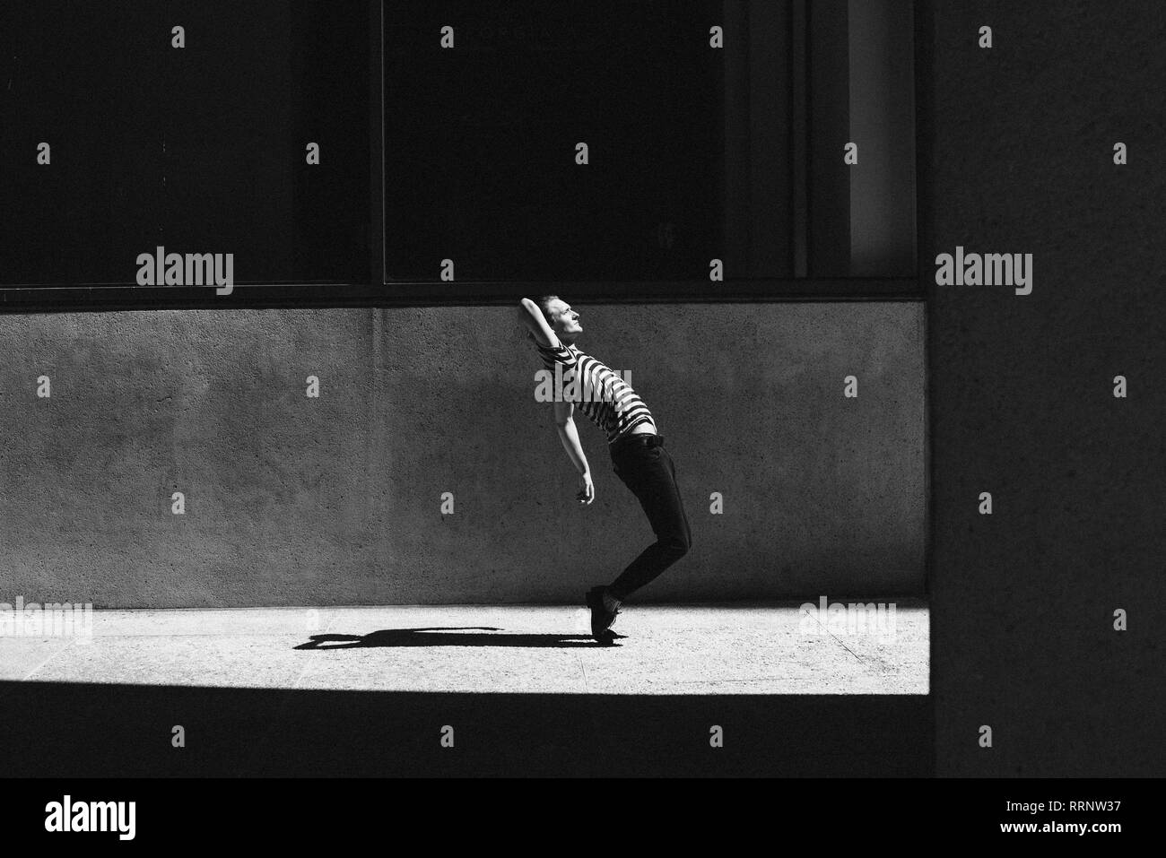 Jeune homme dansant sur trottoir urbain Banque D'Images
