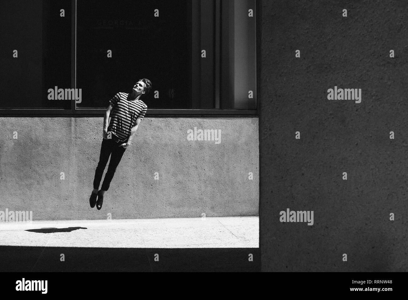 Jeune homme sautant sur trottoir urbain Banque D'Images