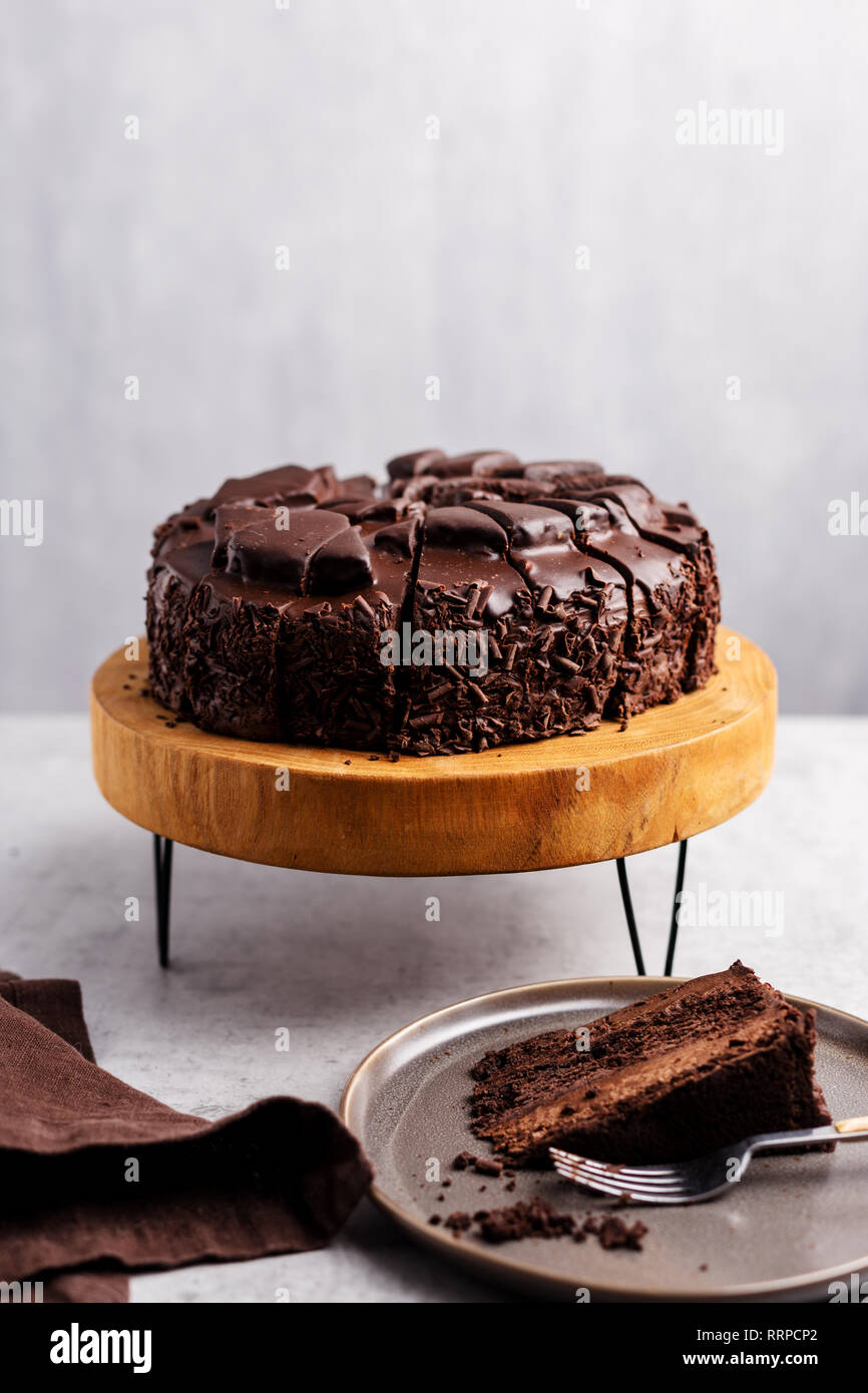 Gâteau au chocolat sur le stand avec tranche de gâteau au chocolat sur la plaque avec la fourchette et serviette verticale, l'espace libre. Concept de fête nourriture sucrée Banque D'Images Gâteau au chocolat sur le stand avec tranche de gâteau au chocolat sur la plaque avec la fourchette et serviette verticale, l'espace libre. Concept de fête nourriture sucrée Banque D'Images