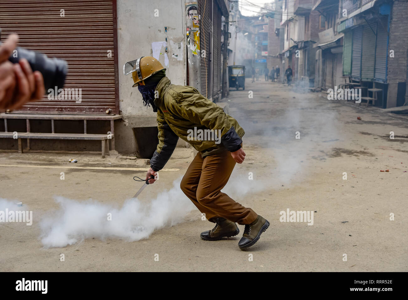 Un policier indien vu jeter des gaz lacrymogènes à Shell de fumée pendant les affrontements à Srinagar. Les forces indiennes au Cachemire sous administration indienne ont utilisé des gaz lacrymogènes pour réprimer les manifestations contre les raids sur les principaux leaders indépendantistes indiennes par les agents de renseignements. Banque D'Images