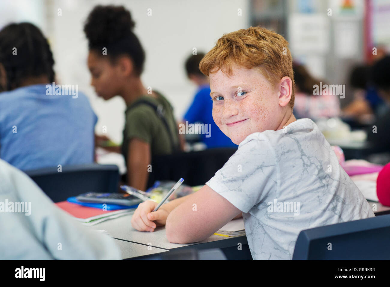 Portrait souriant, confiant junior high school boy student studying in classroom Banque D'Images