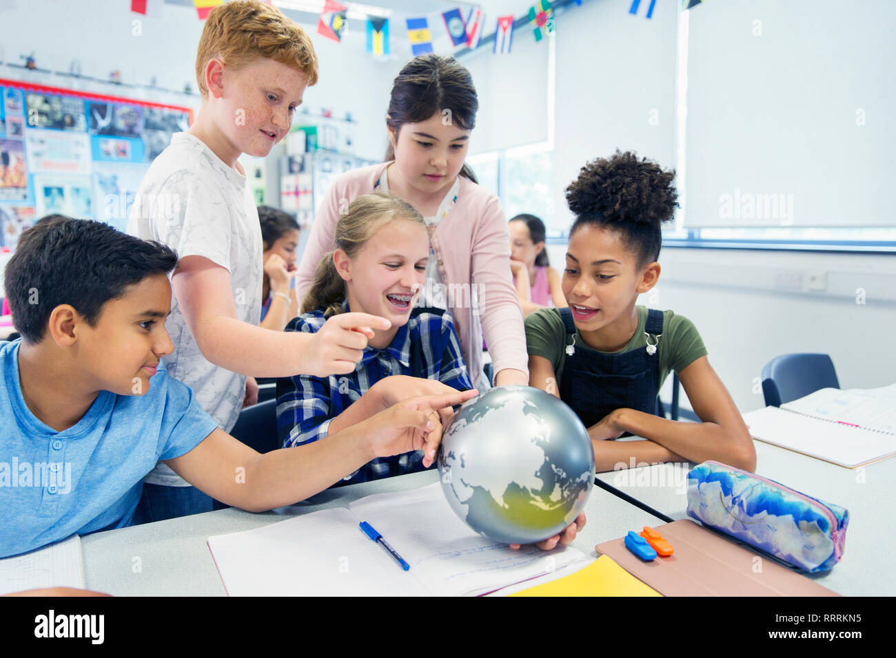 Curieux junior high school students looking at globe in classroom Banque D'Images