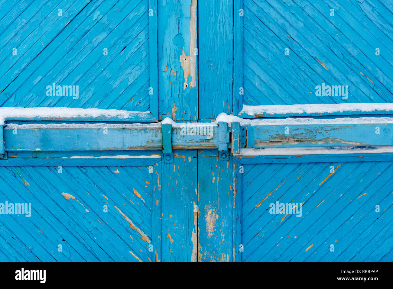 Barrière en bois recouvert de neige blanche. Motif coloré bleu de planches. Porte fermée sur l'ancienne vis. Banque D'Images