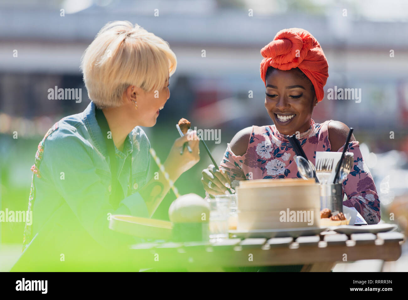 Les jeunes femmes friends enjoying dim sum déjeuner au café avec terrasse ensoleillée Banque D'Images
