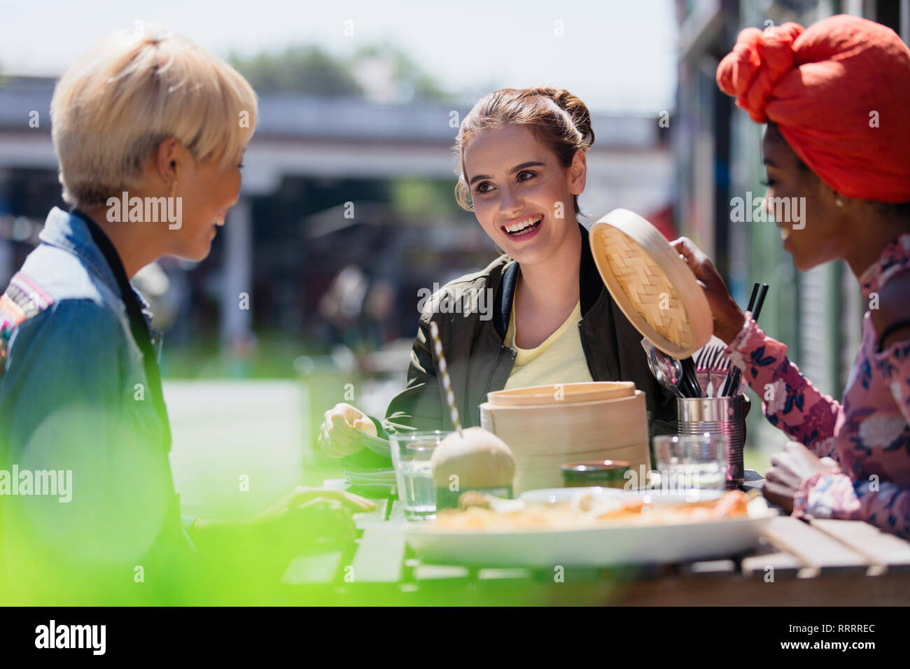 Les jeunes femmes les amis de manger des dim sum déjeuner au café avec terrasse ensoleillée Banque D'Images