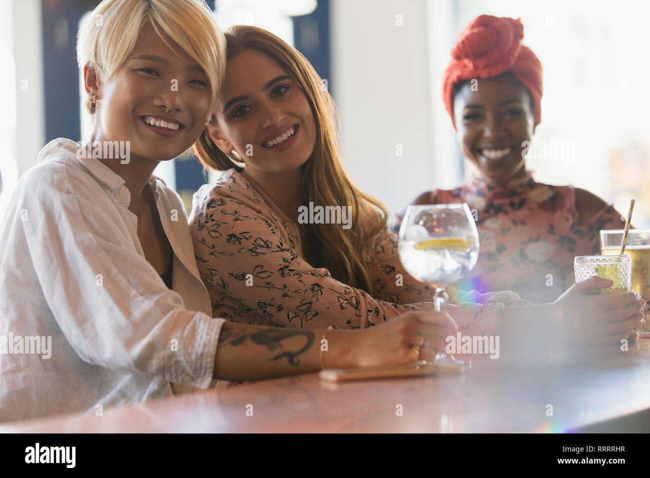 Portrait smiling young women friends drinking cocktails au bar Banque D'Images