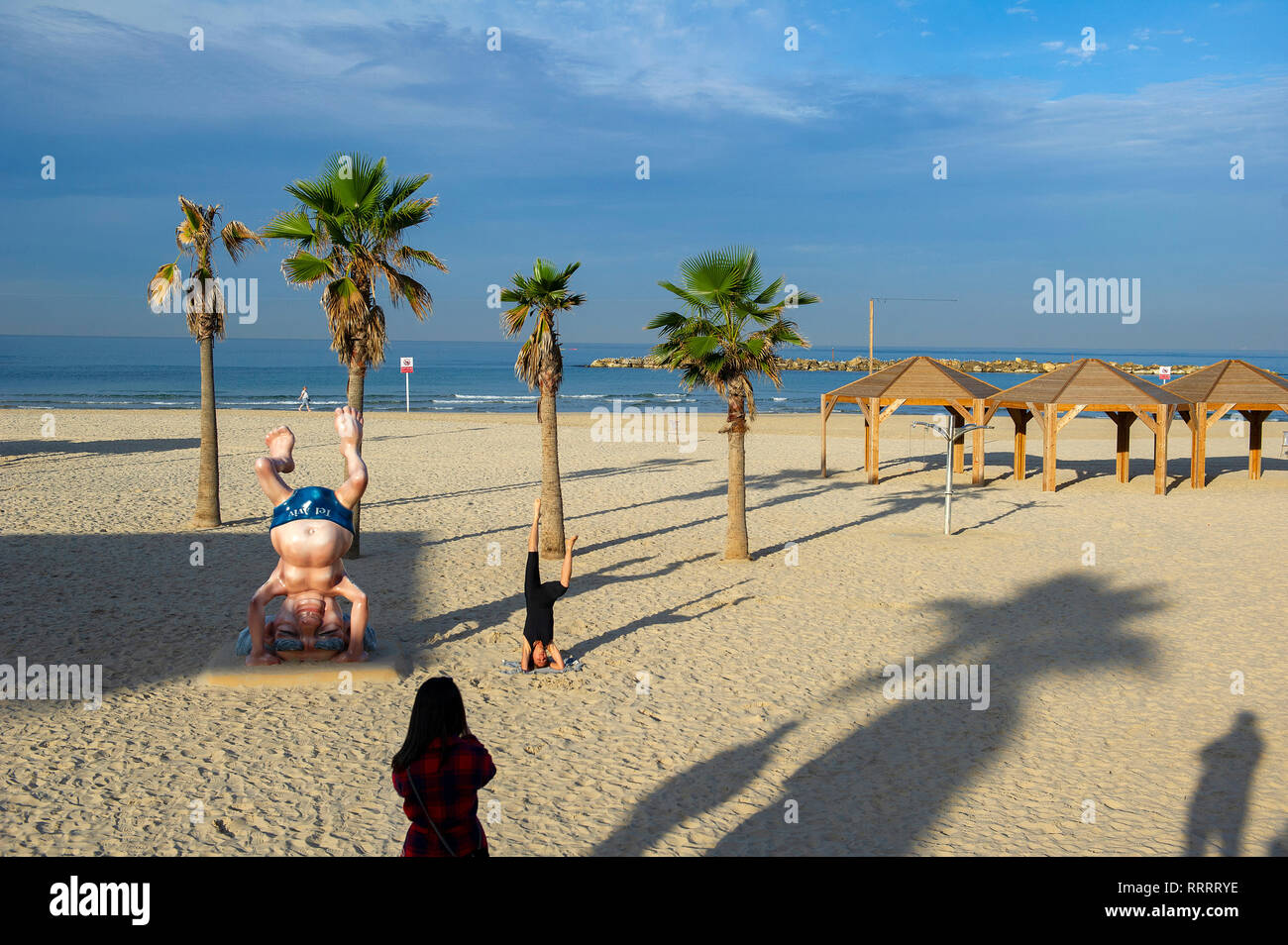 Jeune femme de prendre une photo de son ami faisant une tête à côté de la statue de Ben Gourion sur la plage à Tel Aviv, Israël Banque D'Images