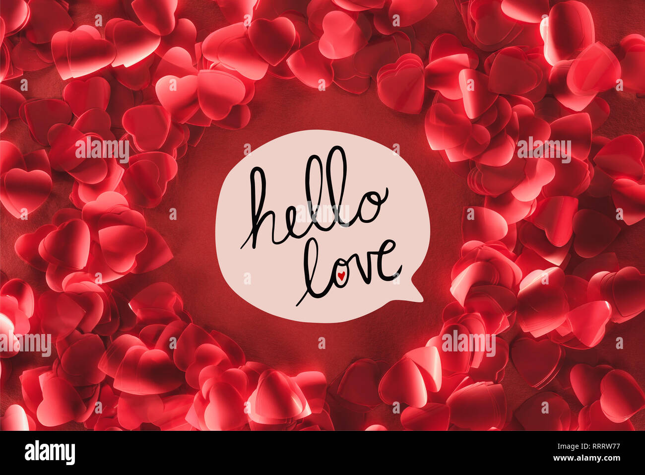 Vue de dessus du châssis belle ronde décorative en forme de coeur pétales sur fond rouge avec 'bonjour love' lettrage, valentines day concept Banque D'Images