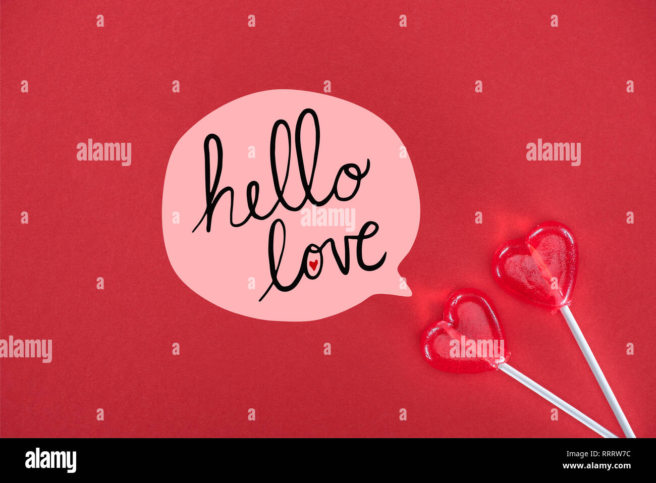 Vue de dessus deux sucettes en forme de coeur sur fond rouge avec 'bonjour love' lettrage, valentines day concept Banque D'Images