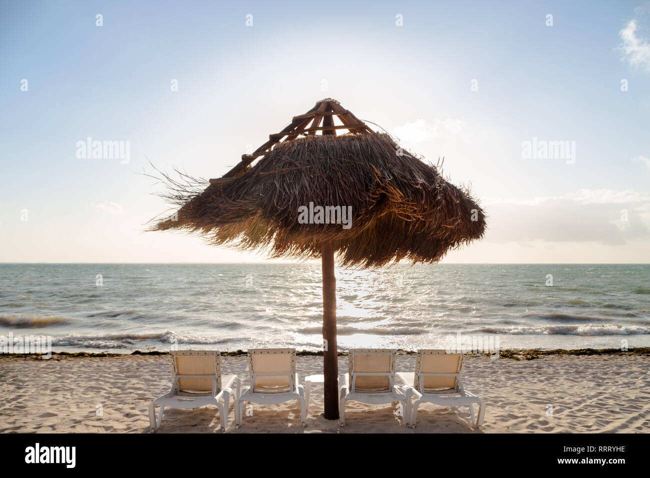 Chaises de plage sur une plage de sable blanc avec un parapluie de style Palapa. Banque D'Images