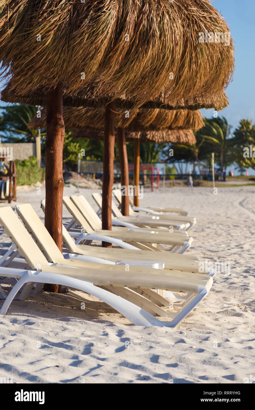 Chaises de plage sur une plage de sable blanc avec un parapluie de style Palapa. Banque D'Images