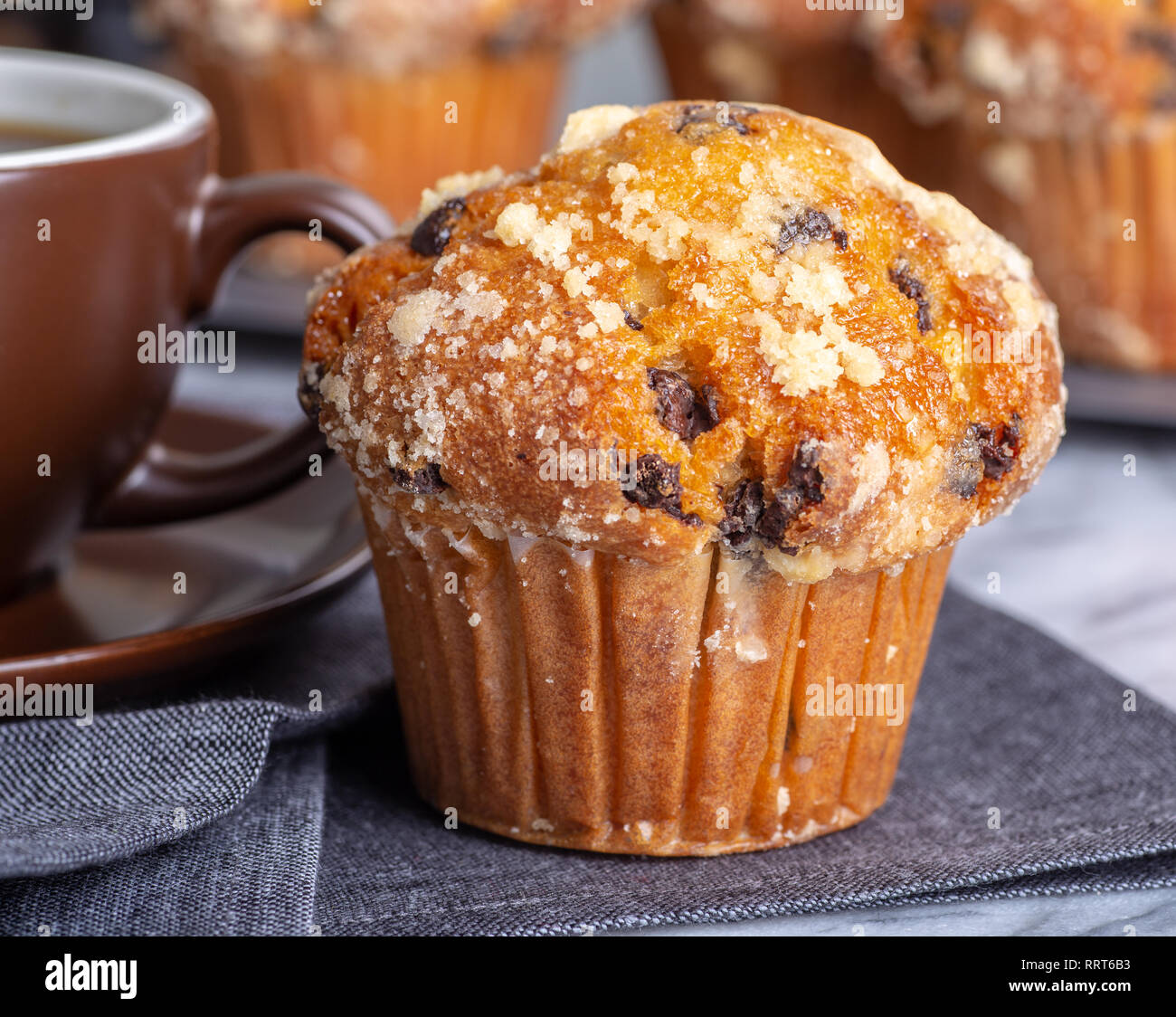 Libre d'un muffin aux pépites de chocolat avec une tasse de café et muffins en arrière-plan Banque D'Images