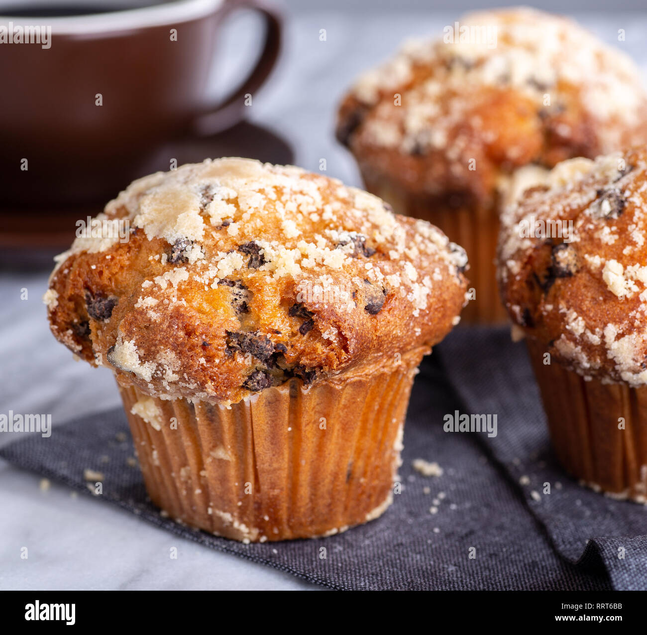 Libre d'un muffin aux pépites de chocolat avec une tasse de café et muffins en arrière-plan Banque D'Images