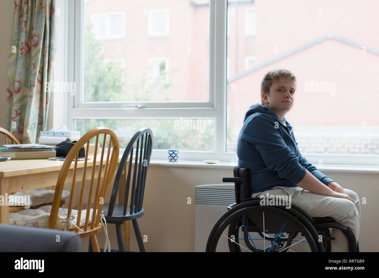 Confiant Portrait young woman sitting in wheelchair at window Banque D'Images