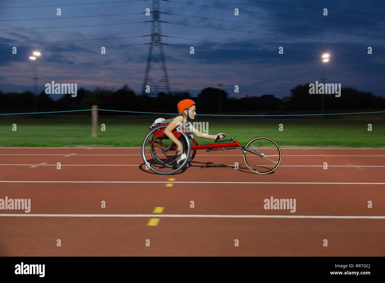 Teenage girl athlète paraplégique en fauteuil roulant sur la piste de course sports la nuit Banque D'Images