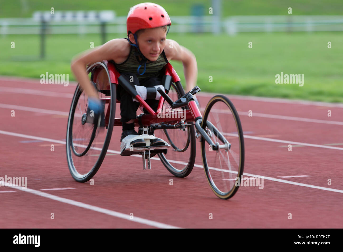 Déterminé, tenace adolescente athlète paraplégique en accélérant le long de la piste en course en fauteuil roulant de sport Banque D'Images