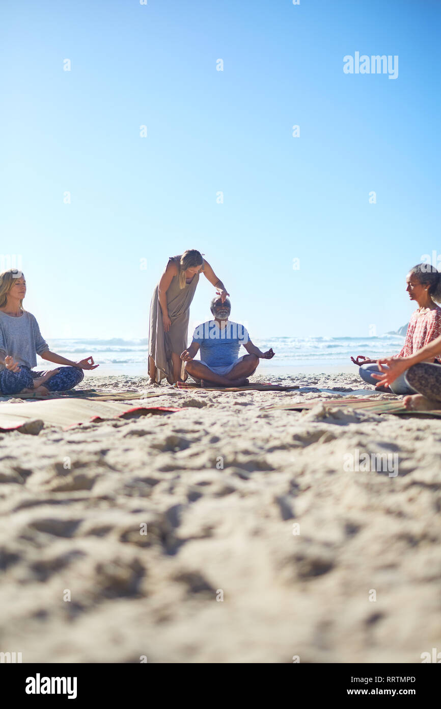Serene personnes méditant sur sunny beach au cours de yoga retreat Banque D'Images