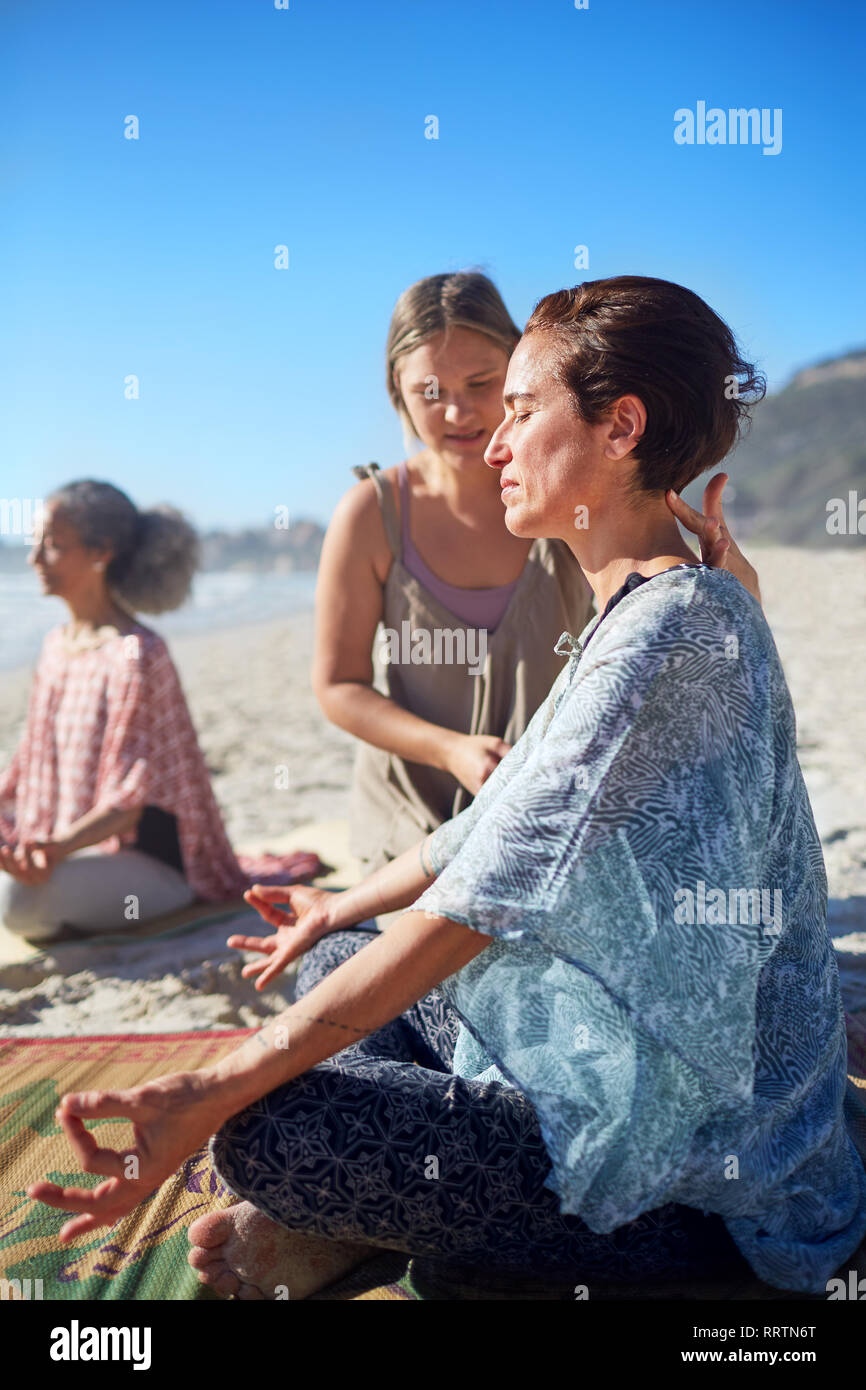 Serene woman meditating on sunny beach au cours de yoga retreat Banque D'Images