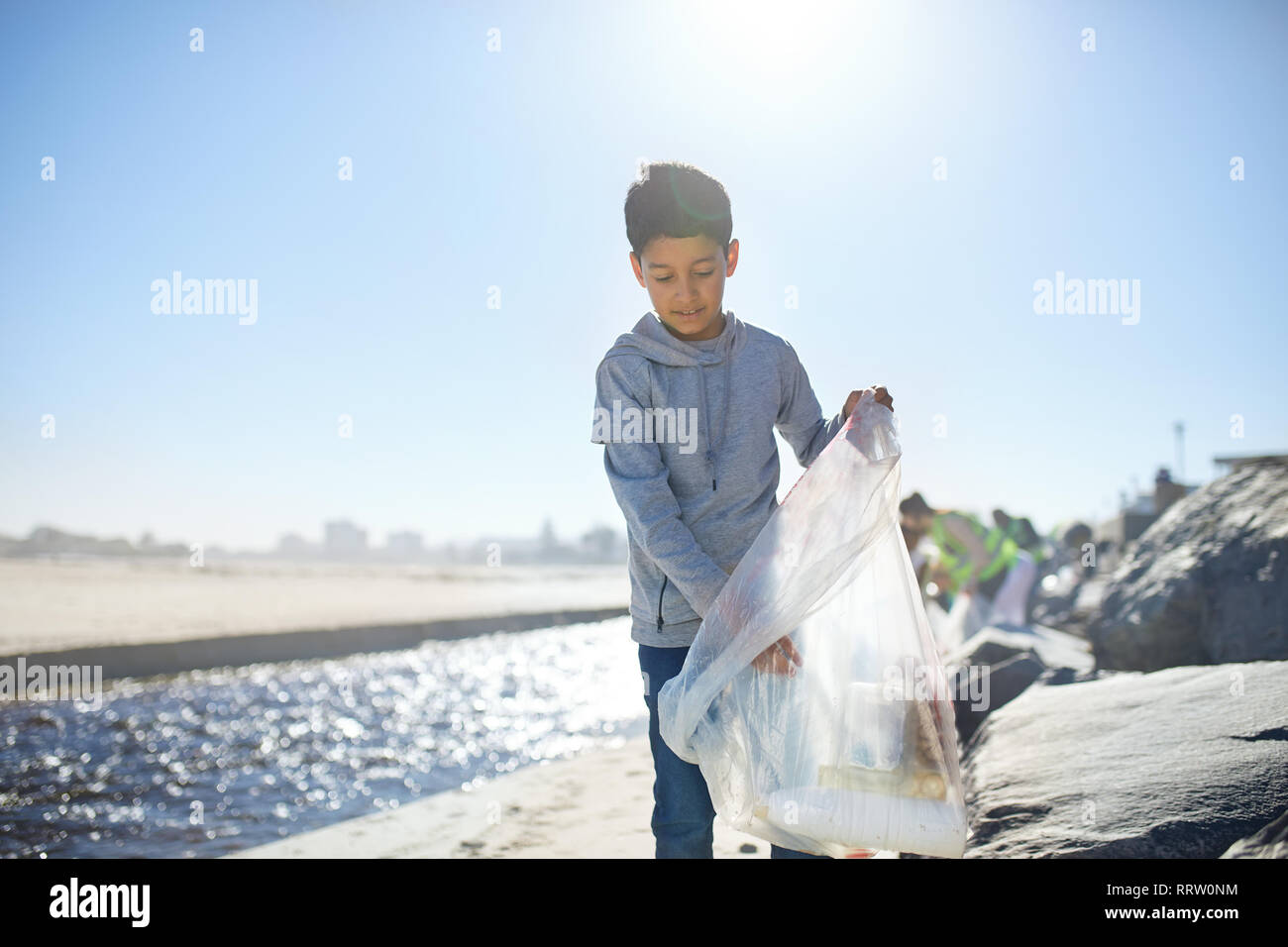 Les déchets de nettoyage bénévole garçon sur sunny beach Banque D'Images