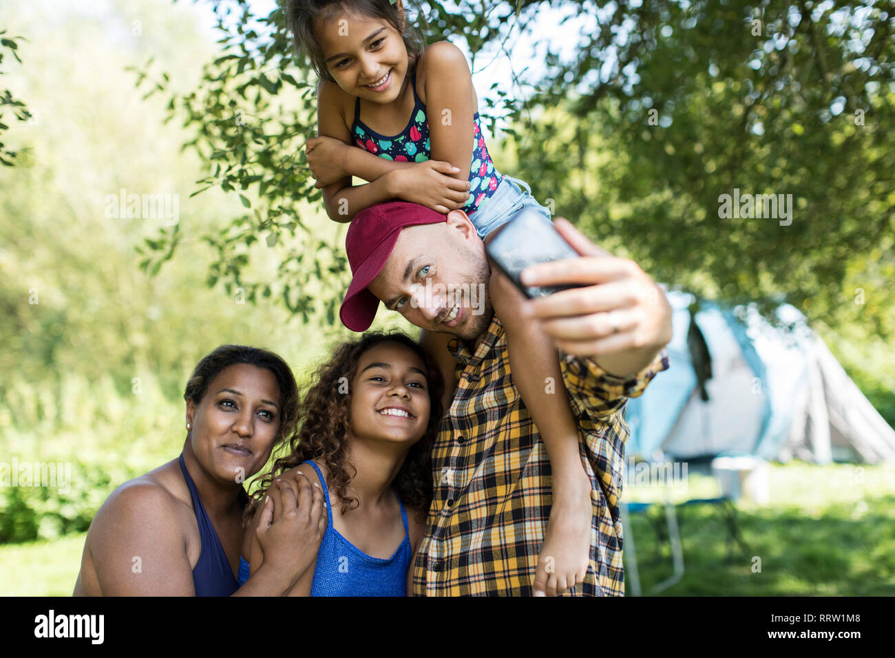 Heureux, affectueux avec la famille en tenant l'appareil photo au téléphone selfies camping Banque D'Images