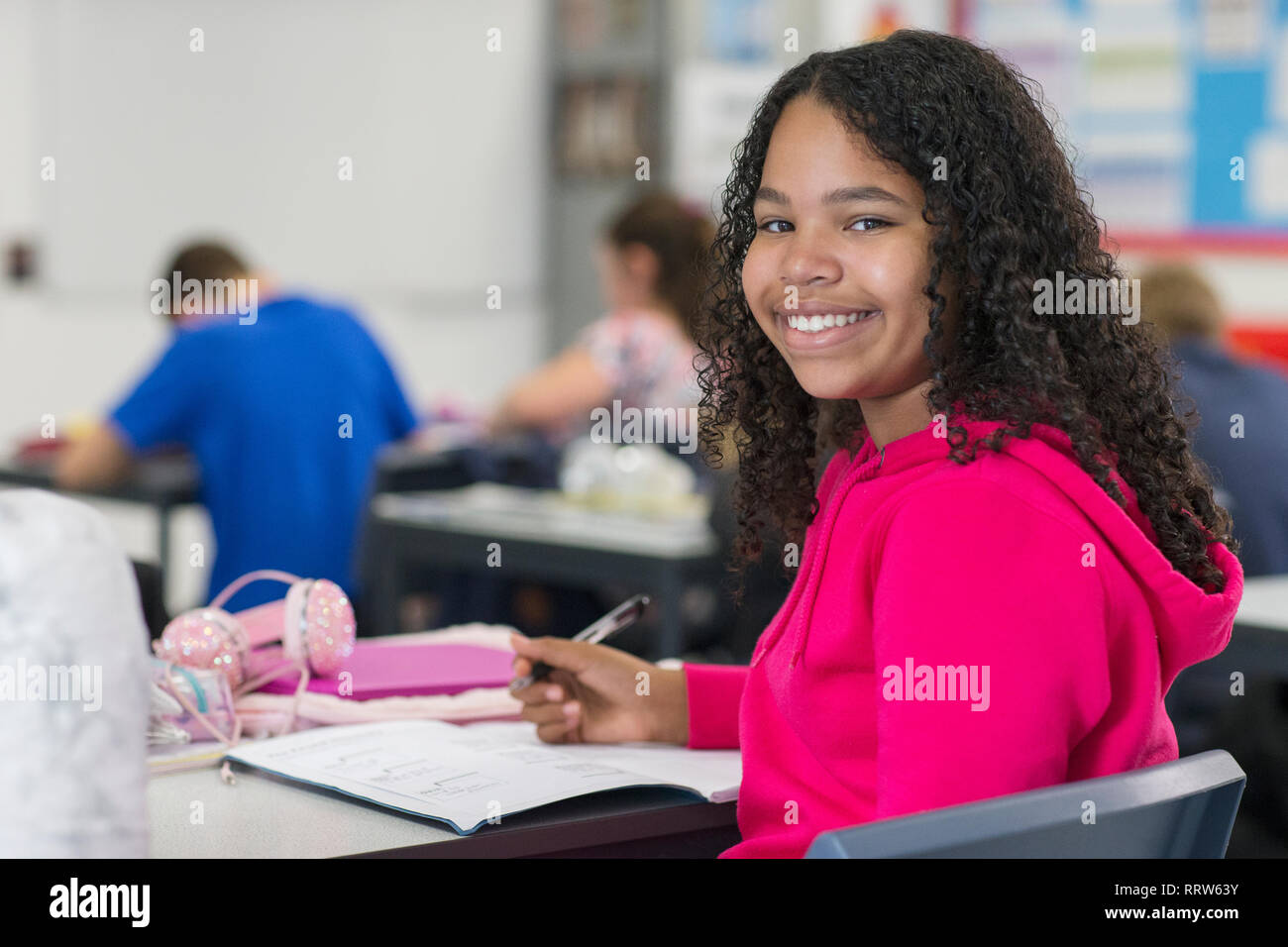 Portrait confiant junior high school student girl doing Homework in classroom Banque D'Images