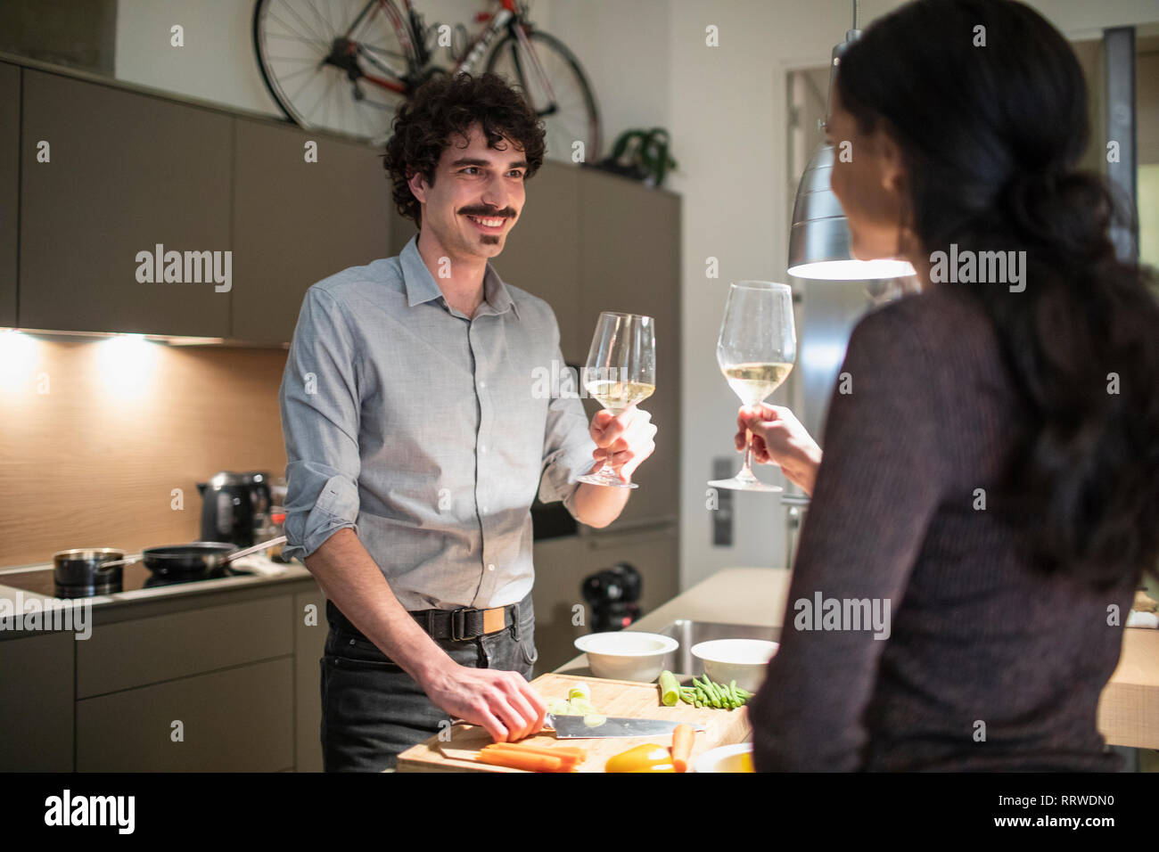 Couple en train de préparer le dîner et boire le vin blanc dans la cuisine de l'appartement Banque D'Images