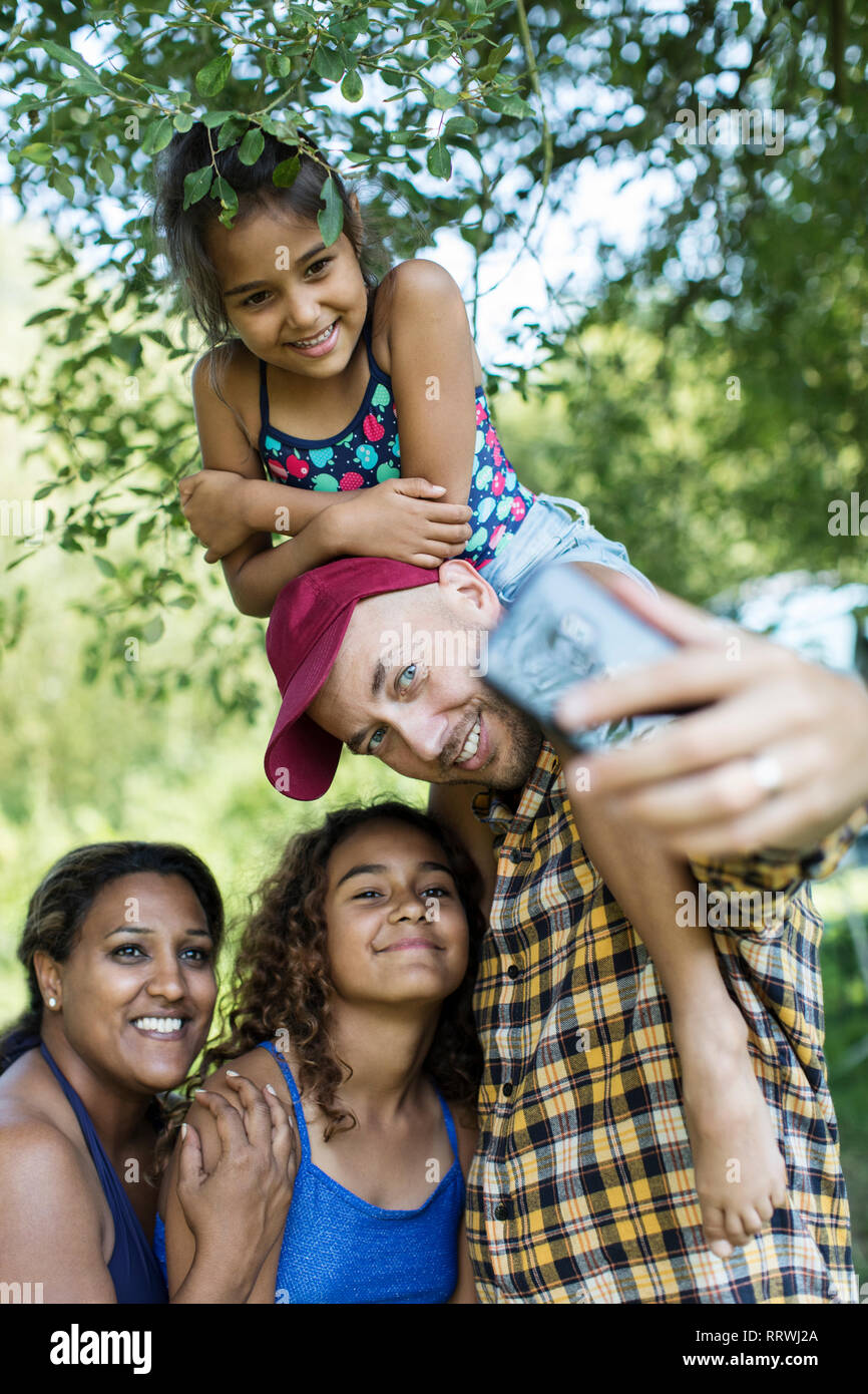 Heureux, affectueux en tenant la famille téléphone-appareil photo avec selfies Banque D'Images