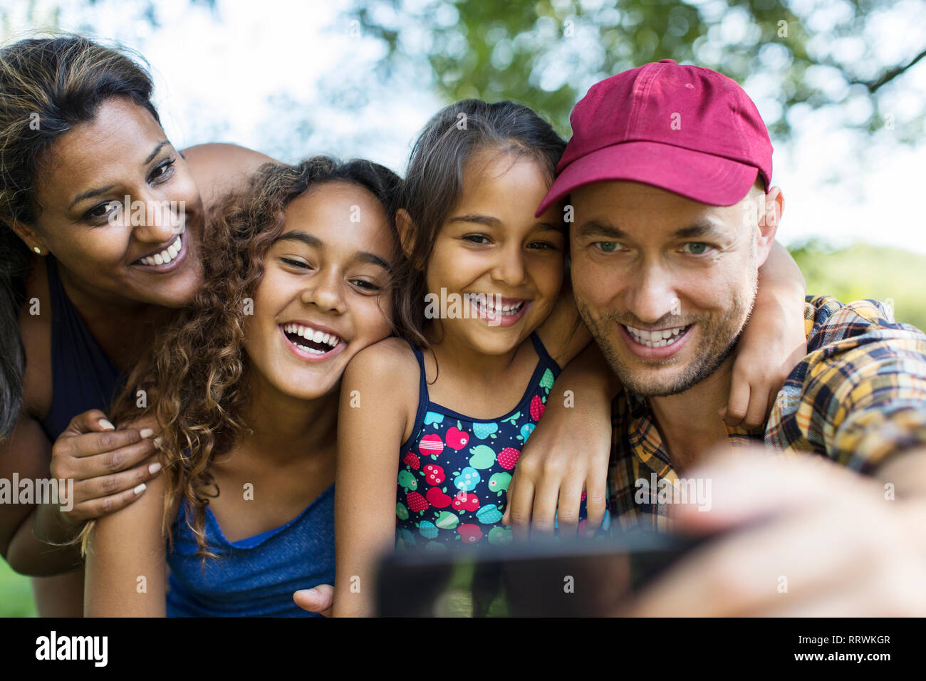 Famille heureuse en tenant avec selfies téléphone appareil photo Banque D'Images