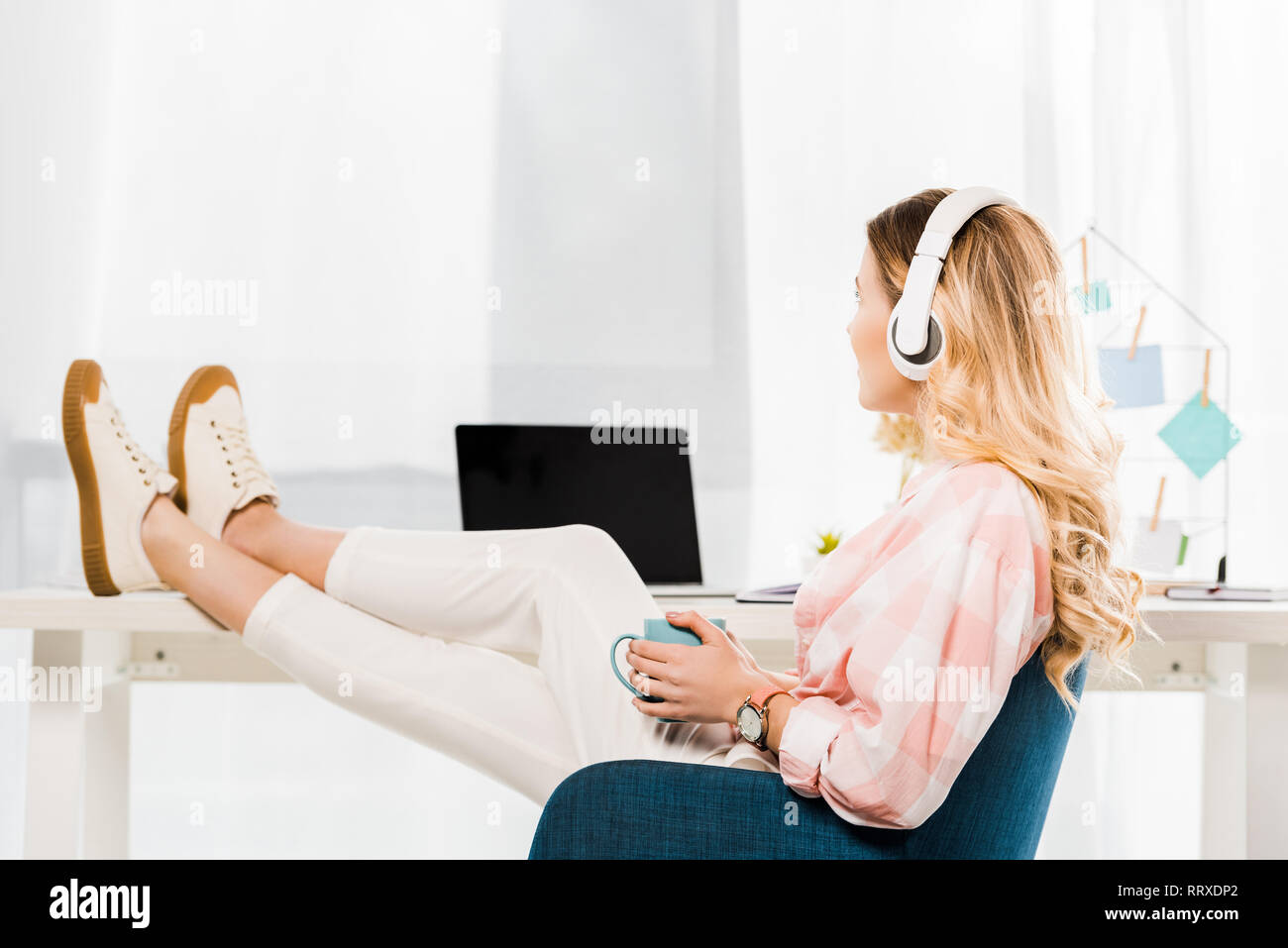 Jeune femme détendue avec café tasse listening music at home office Banque D'Images