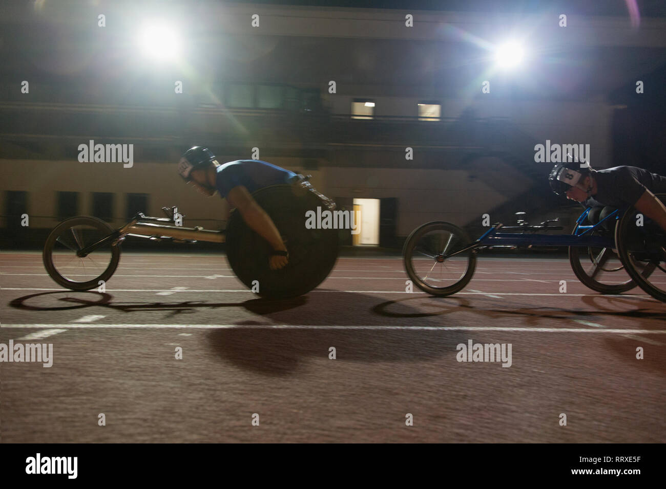 Athlète paraplégique en accélérant le long de la piste de course en fauteuil roulant au cours de sport Banque D'Images