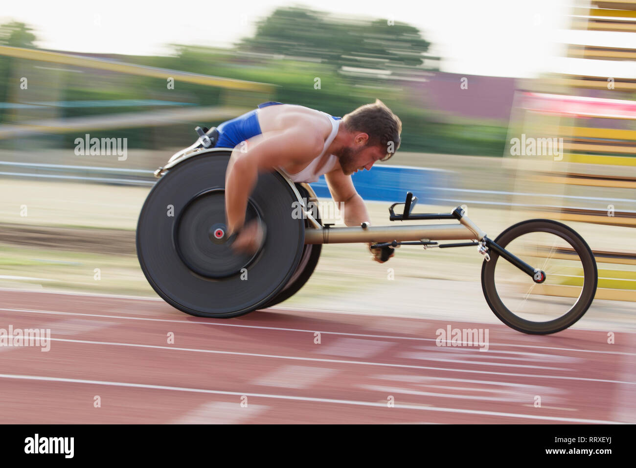 Jeune homme déterminé de vitesse sur piste sports paraplégiques en course en fauteuil roulant Banque D'Images