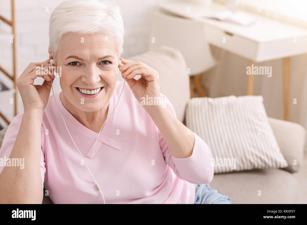 Ravi aged woman listening to music at home Banque D'Images