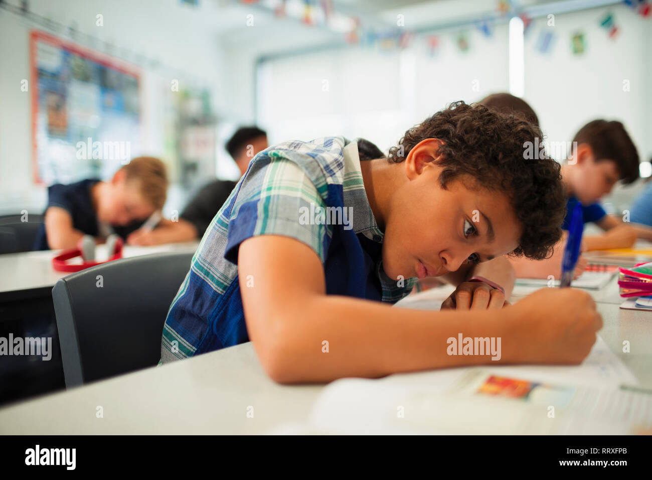 L'accent junior high school boy doing Homework in classroom Banque D'Images