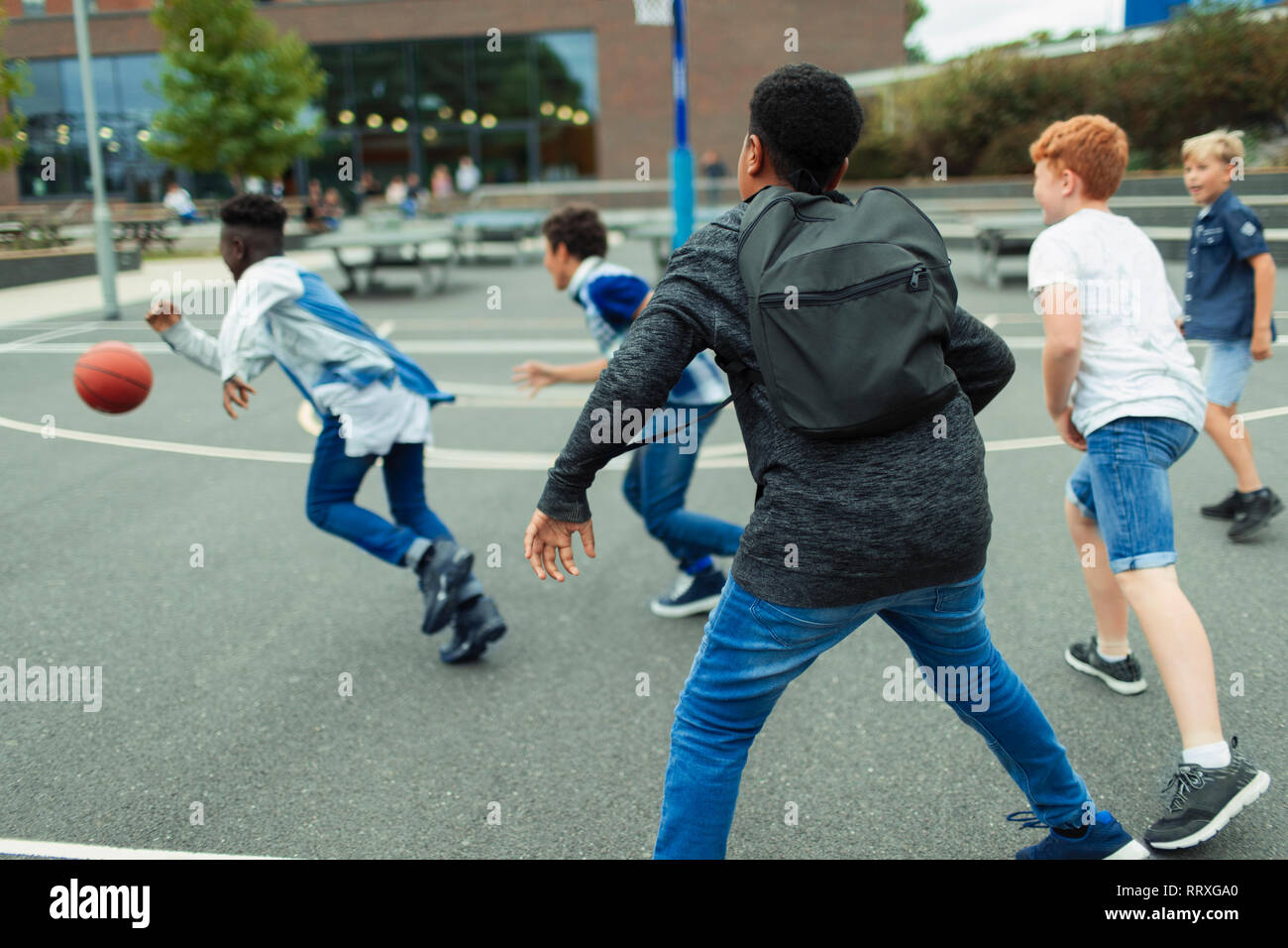 Les étudiants de premier cycle Garçon jouant au basket-ball dans l'école Banque D'Images Les étudiants de premier cycle Garçon jouant au basket-ball dans l'école Banque D'Images