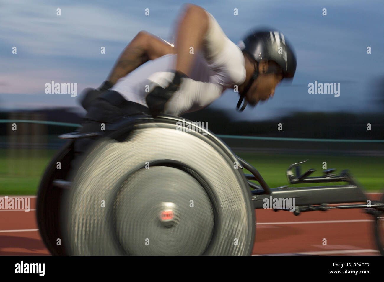 Athlète paraplégique en accélérant le long de la piste en course en fauteuil roulant de sport Banque D'Images