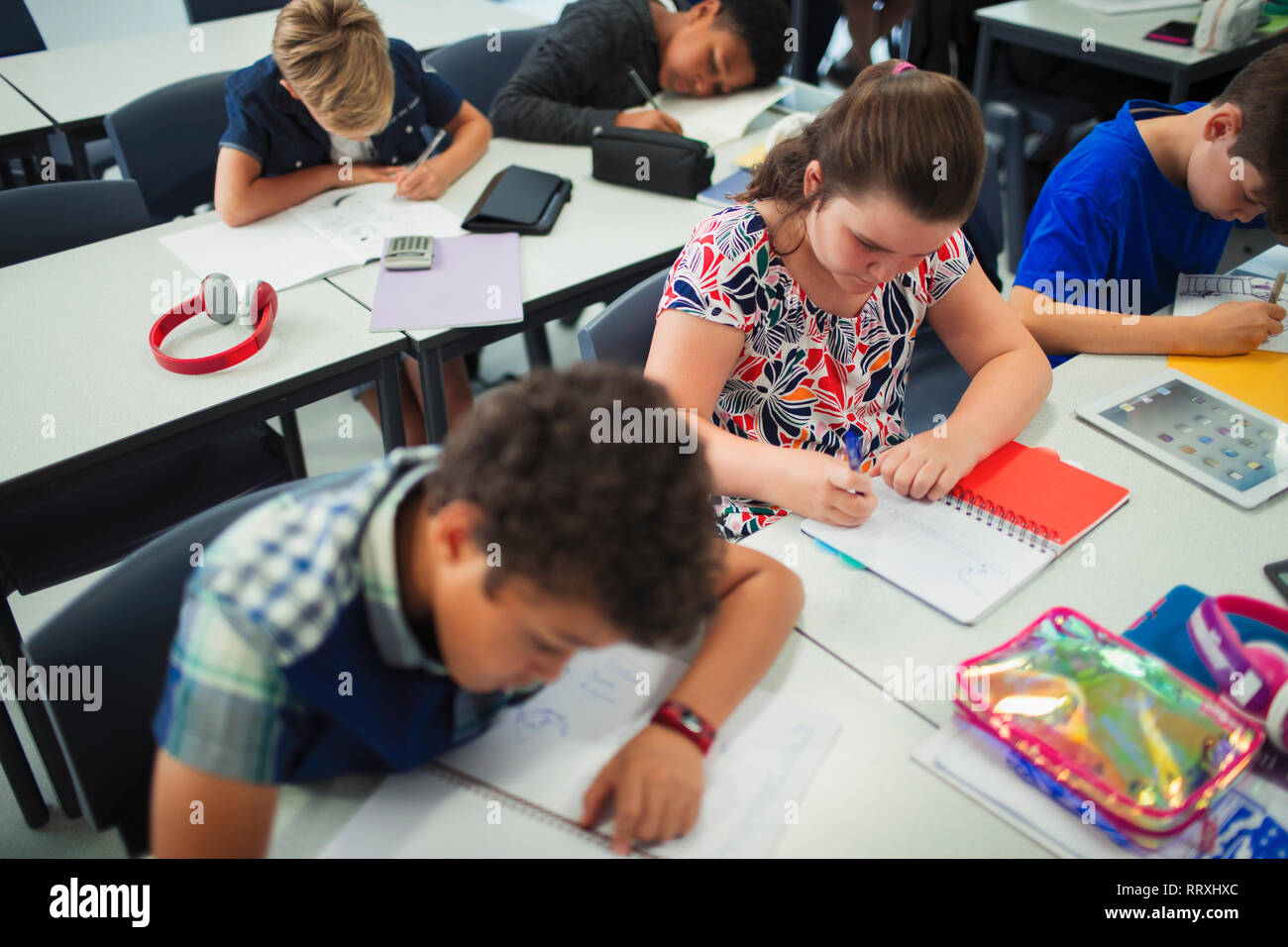 Des élèves du premier cycle du secondaire à faire leurs devoirs à un bureau dans la salle de classe Banque D'Images