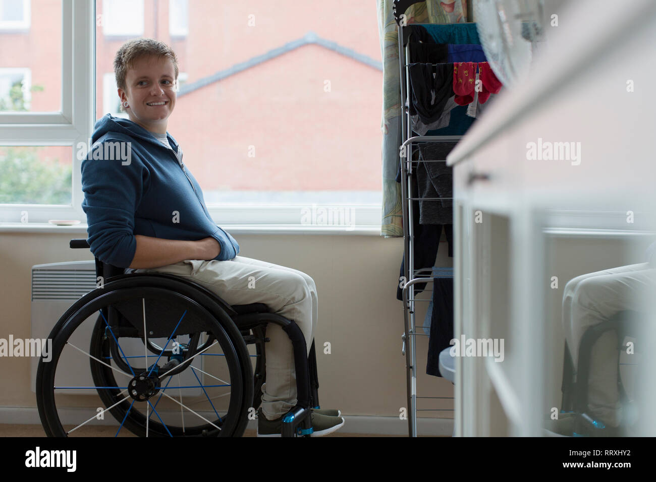 Confiant Portrait young woman sitting in wheelchair at window Banque D'Images